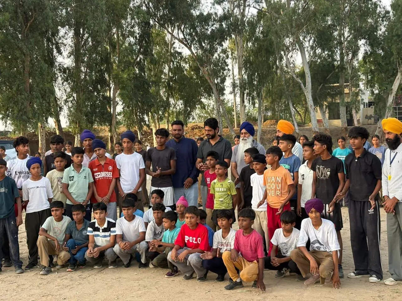A large group of children and adults on a sports ground lined with eucalyptus trees