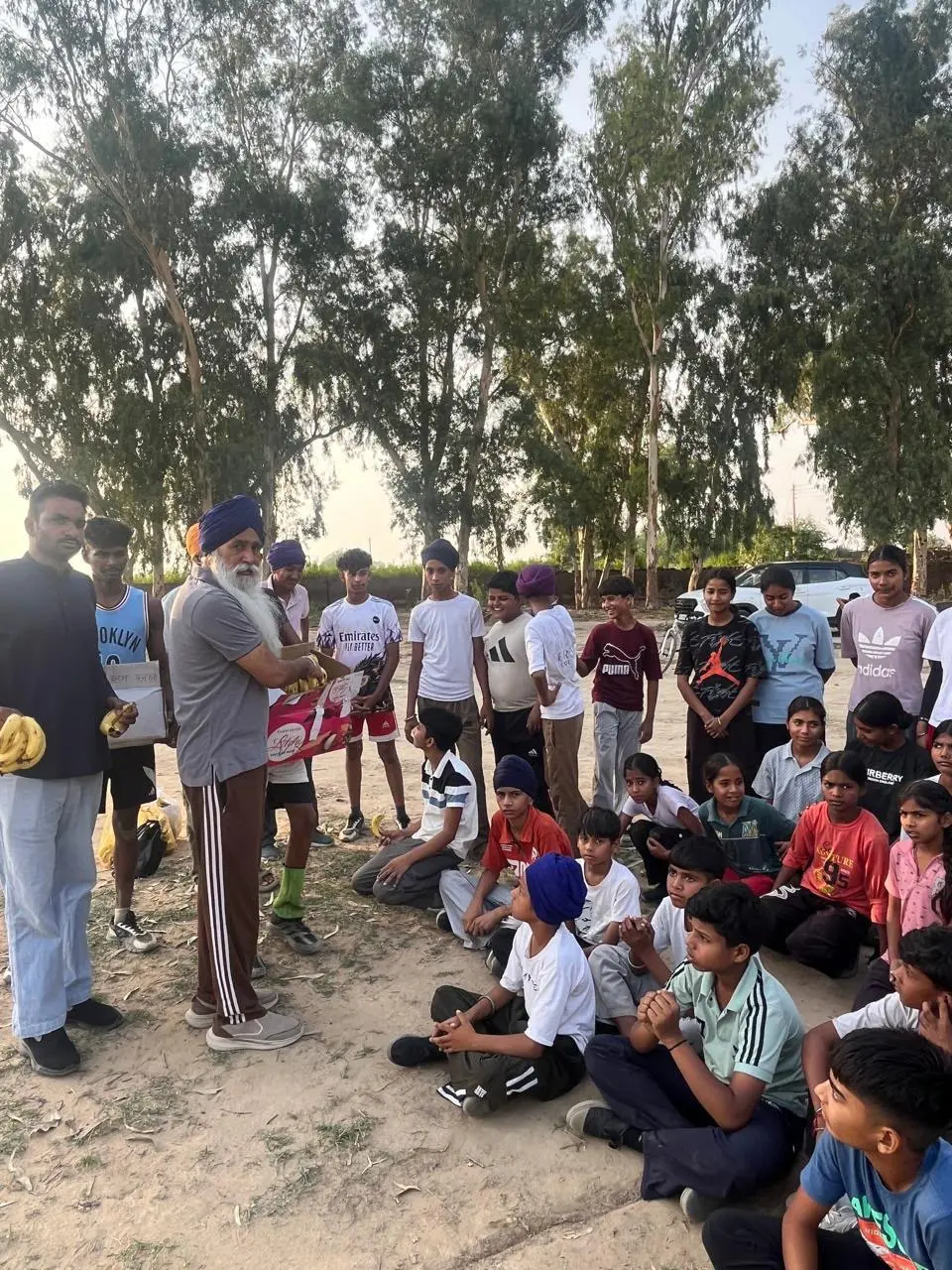 Fruit being handed out to children seated on a sports ground