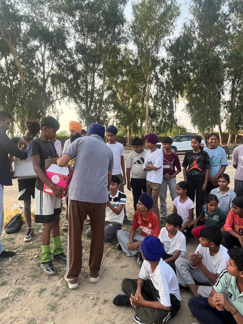 Boxes being handed out to children on a sports ground at dusk