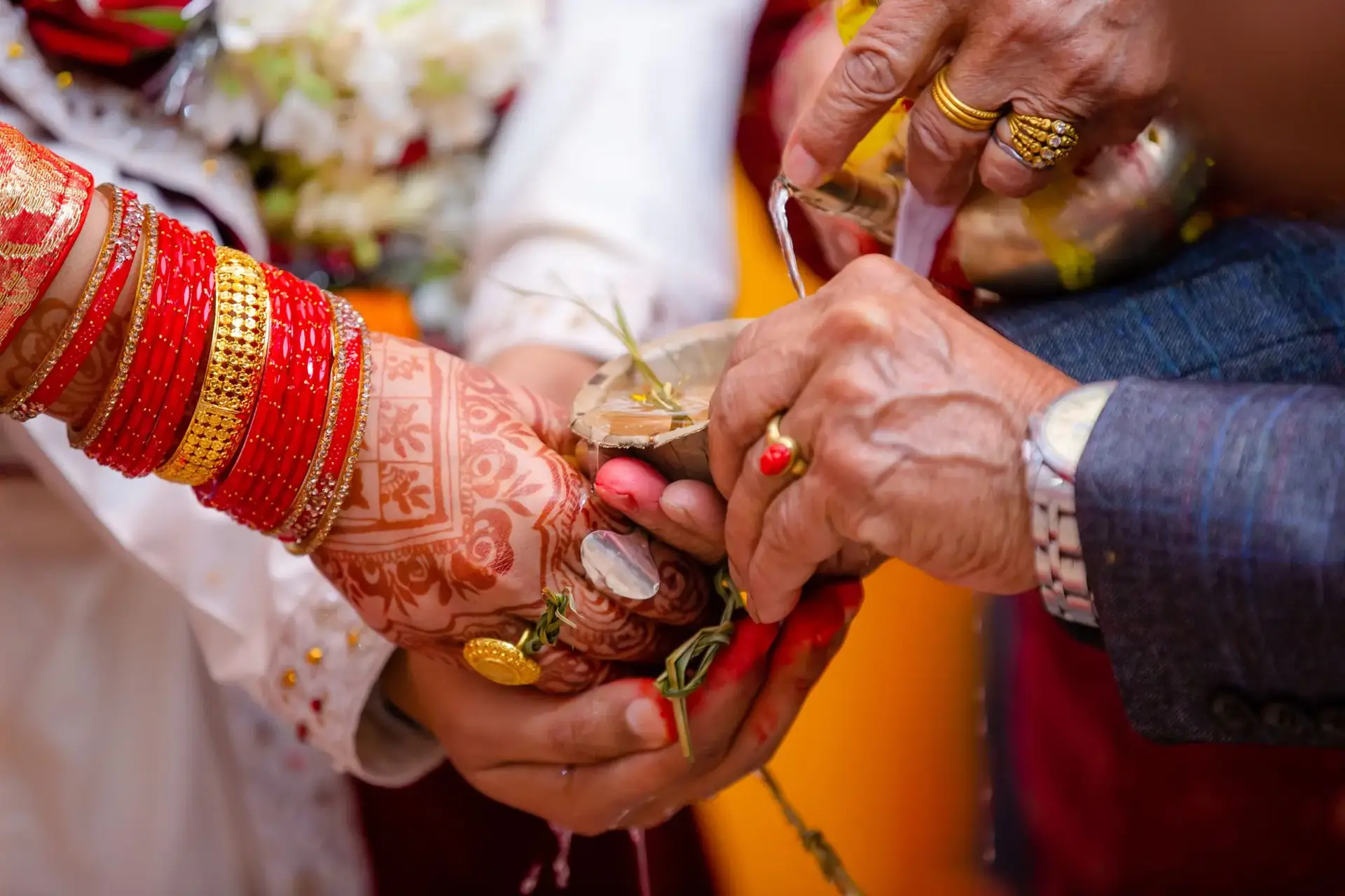 Hands joined in a wedding ritual, the bride's wrists in red bangles and mehndi